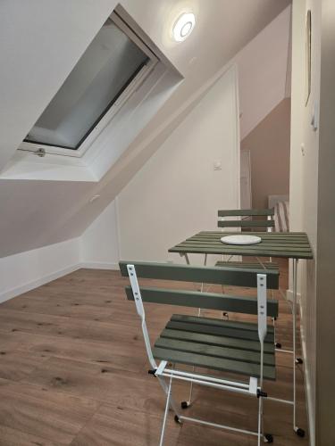 Cette chambre mansardée dispose de chaises vertes et d'une table. dans l'établissement Combles dans le quartier de la gare de Strasbourg, à Strasbourg