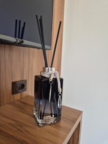 a vase with sticks in it sitting on a table at Harmonioso Ap Sete lagoas in Sete Lagoas