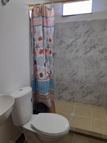 a bathroom with a toilet and a shower curtain at La Vaca Fifí in Murillo