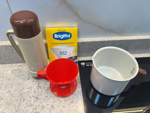 a coffee maker on a counter next to a measuring cup at Aconchego e paz no Centro de Vila Velha in Vila Velha
