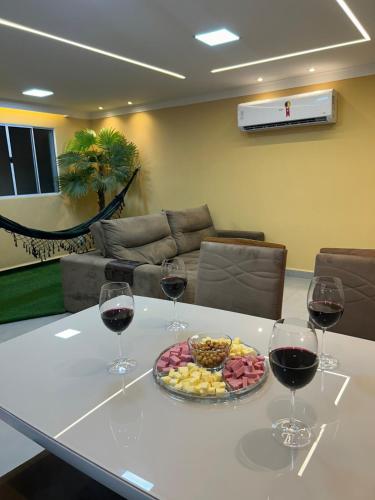 a table with two glasses of wine and a tray of food at Aconchego e paz no Centro de Vila Velha in Vila Velha