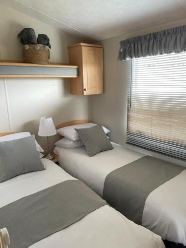 two beds in a small room with a window at Meadow & Tide in Saint Merryn