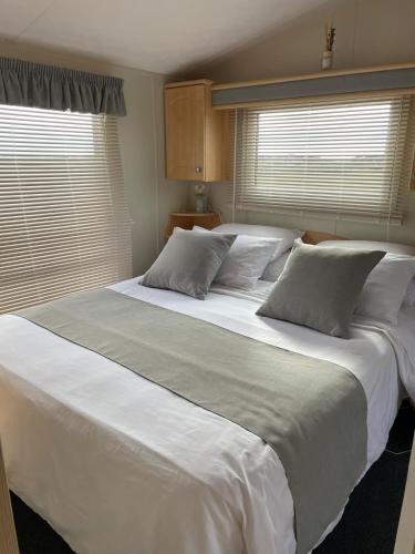 a large white bed in a bedroom with two windows at Meadow & Tide in Saint Merryn