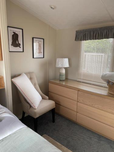 a bedroom with a bed and a chair and a window at Meadow & Tide in Saint Merryn