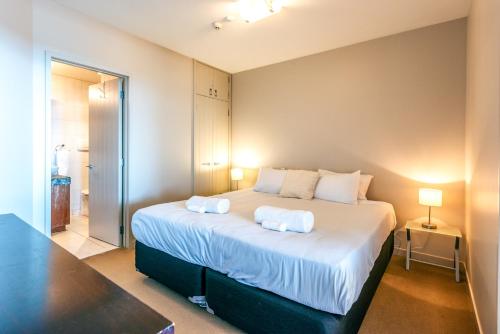 a bedroom with a large bed with two pillows on it at The Sands Apartment 6 - Stay Waiheke in Waiheke Island