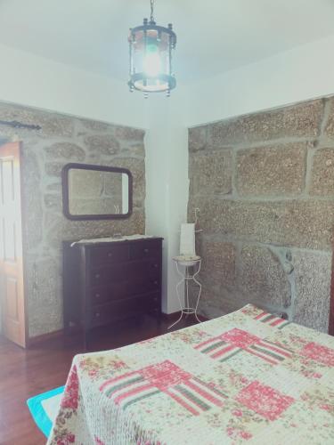 a bedroom with a bed and a stone wall at Casa da Calçada in Arcos de Valdevez