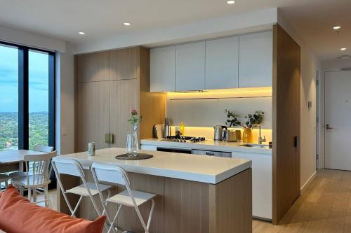 a kitchen with a island with chairs and a counter top at Sky One Harmony in Box Hill