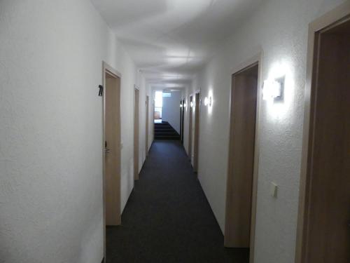 a corridor of a hallway with white walls and lights at Hotel KRONE Garni in Deckenpfronn