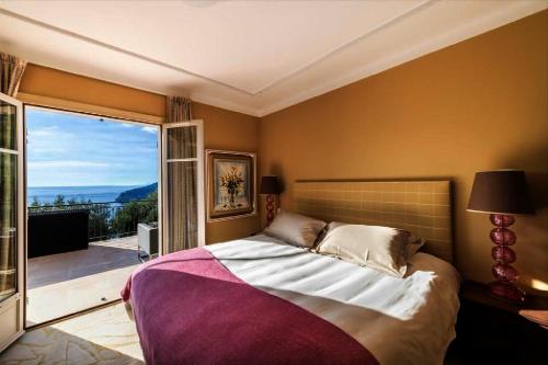 une chambre avec un grand lit et une grande fenêtre dans l'établissement Villa located in a luxurious area, à Villefranche-sur-Mer