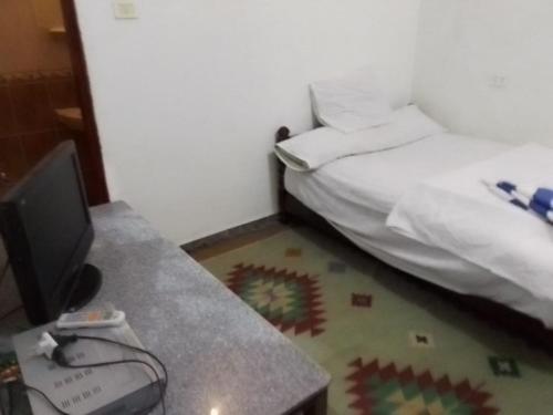 a room with a bed and a desk with a television at One Love Guesthouse & Restaurant in Luxor