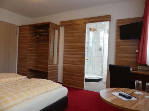 a hotel room with a bed and a desk and a table at Hotel KRONE Garni in Deckenpfronn