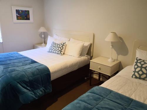a bedroom with two beds and a night stand with two lamps at Tuscana Motor Lodge in Christchurch