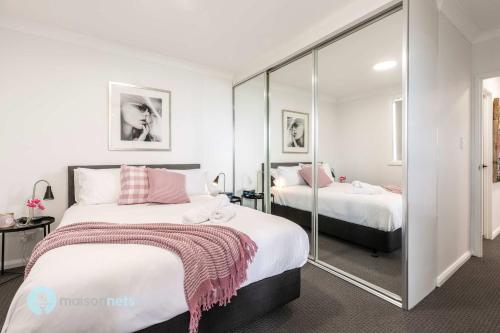 a bedroom with two beds and a mirror at 2 Bedroom 2 Bathroom Apt with Balcony and Parking in Sydney