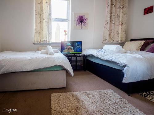 a bedroom with two beds and a tv on a table at WoodHus Lodge Fantastic Large Double Room 3 in Stoke on Trent