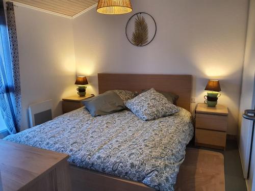a bedroom with a bed with two night stands and two lamps at Appartement cosy et climatisé pour 1 à 4 personnes 150m place Gambetta in Casteljaloux