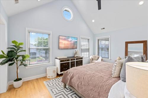 Luxurious OC Single Family Home with Hot Tub في أوشن سيتي: غرفة نوم بسرير وتلفزيون ونوافذ