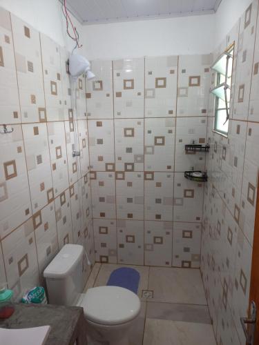 a bathroom with a toilet and a wall of tiles at Ar condicionado ! Pousada familiar natureza Rustic in Ilha Comprida