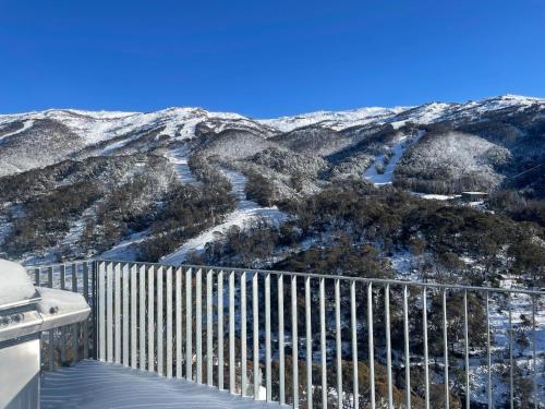 a view of a snow covered mountain with a fence at Schuss Alpine Club, Thredbo in Thredbo