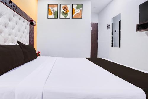 a bedroom with a white bed with a black and white headboard at Super Collection O Asalpha near International Airport in Mumbai