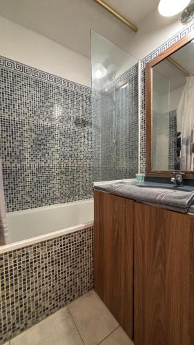 une salle de bain avec une baignoire, un lavabo et un miroir dans l'établissement Cannes Beach appartements - Piscine proche mer, à Cannes