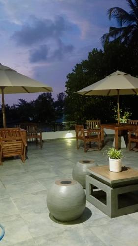 a patio with tables and chairs and umbrellas at Villa Mossa Ambalangoda Boutique villa in Ambalangoda