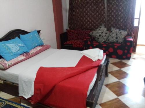 a bedroom with a bed with a red blanket and a chair at One Love Guesthouse & Restaurant in Luxor