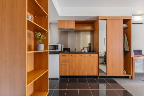 a kitchen with wooden cabinets and a microwave at Punthill Apartment Hotel - Little Bourke in Melbourne