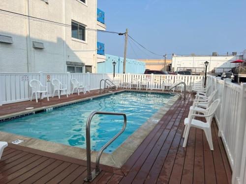 a swimming pool with white chairs on a deck at Modern Condo Just Steps from the OC Boardwalk in Ocean City