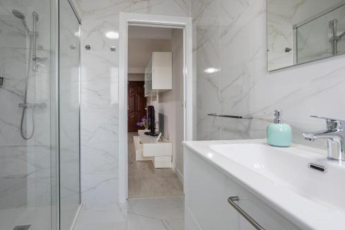 a white bathroom with a sink and a shower at Veigas de Iria - Apartamento Turístico VUT in Padrón