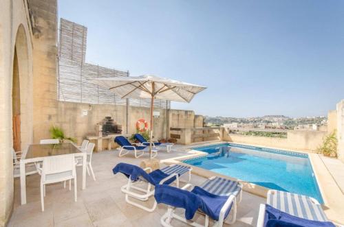 a patio with a table and chairs and a pool at Arkati house in Munxar