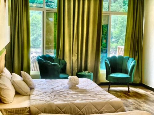 a bedroom with a bed and two chairs and a window at Chinar Resort Keran Neelam Valley in Shāhkot