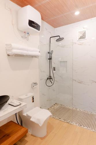 a white bathroom with a shower and a toilet at The Sikarim Waterfall View Villa in Kejajar