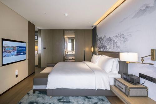 a bedroom with a large bed and a flat screen tv at 青岛海天大酒店 山海相拥典雅奢华 in Qingdao