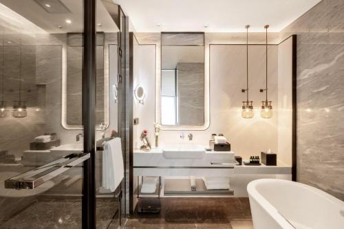 a bathroom with a sink and a tub and a mirror at 青岛海天大酒店 山海相拥典雅奢华 in Qingdao