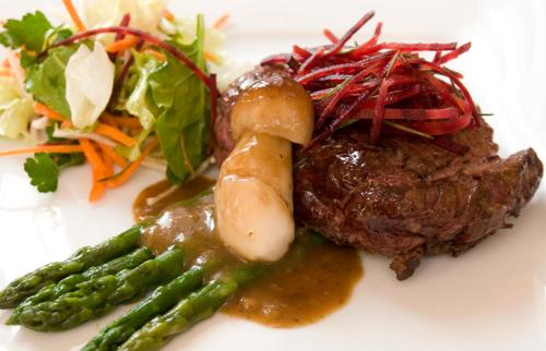 a plate of food with meat and asparagus and a salad at Pietrak Hotel in Gniezno