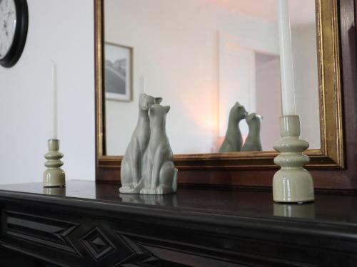 a table with a mirror and three statues on it at Appartement spacieux à Lunéville, proche des attractions - FR-1-584-366 in Lunéville
