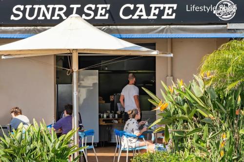 a group of people sitting in chairs under an umbrella at Stunning Family Home with Tropical Garden in Warriewood