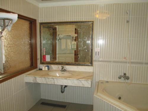 a bathroom with a sink and a mirror and a tub at Huangjia Motel in Tainan