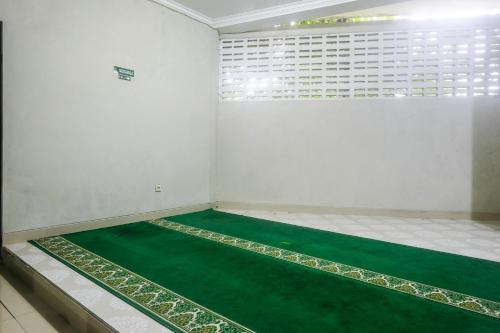 a room with a green floor and a window at Joglo Manggisan Syariah Kotagede Mitra RedDoorz in Yogyakarta