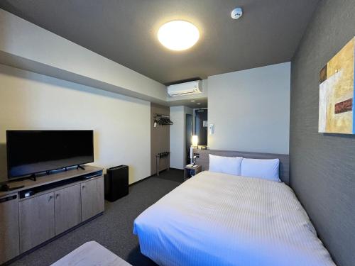 a hotel room with a bed and a flat screen tv at Hotel Route Inn Grand Fukushima Ekimae Higashiguchi in Fukushima