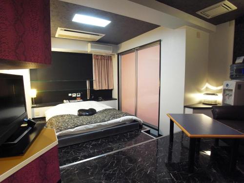 a room with a bed and a table in it at ホテル Tiger & Dragon 男塾ホテルグループ in Gifu