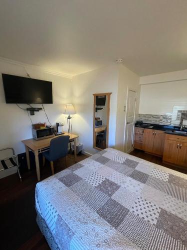 a bedroom with a bed and a desk and a television at Sunset Motel in Cache Creek