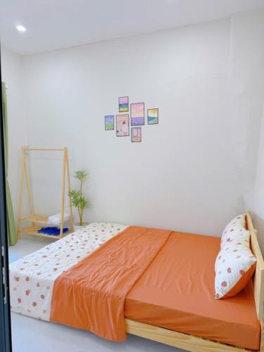 a bed with an orange comforter in a room at Yang Homestay Phan Thiết in Phan Thiet