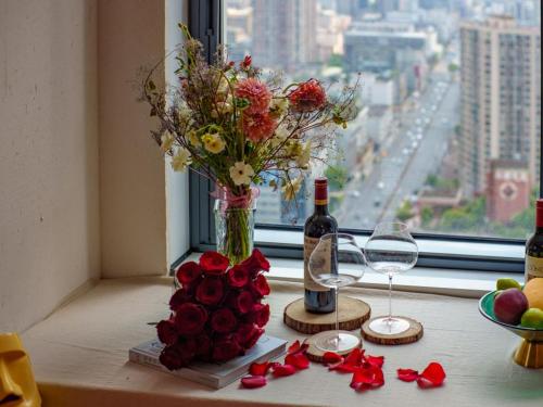 a table with a vase of flowers and a bottle of wine at M Panda Tower Boutique Chengdu in Chengdu