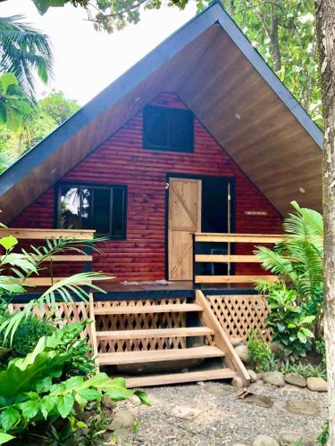 een rood huis met een houten deur en een veranda bij Cabaña Vacal Wifi, beach front #2 in Uvita