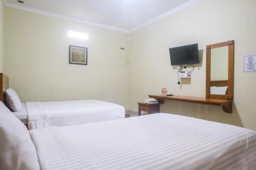 a hotel room with two beds and a tv at Joglo Manggisan Syariah Kotagede Mitra RedDoorz in Yogyakarta