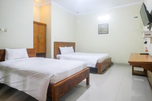 a hotel room with two beds and a television at Joglo Manggisan Syariah Kotagede Mitra RedDoorz in Yogyakarta
