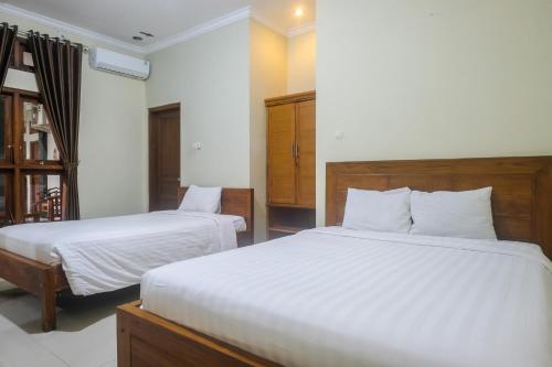 a bedroom with two beds with white sheets at Joglo Manggisan Syariah Kotagede Mitra RedDoorz in Yogyakarta