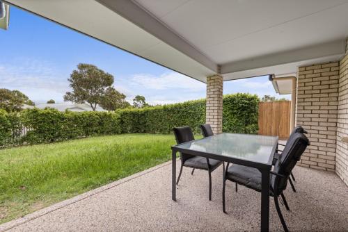 a table and chairs on a patio with a lawn at Charming 3-Bed Home Near Sunshine Coast in Caloundra West