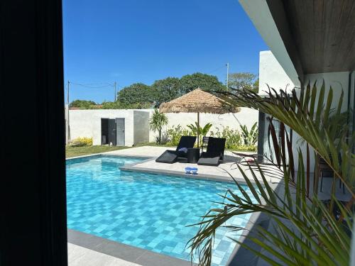 a swimming pool with two lounge chairs and an umbrella at 4BR Villa with Pool in Calatagan Batangas up to 16 Guests in Calatagan